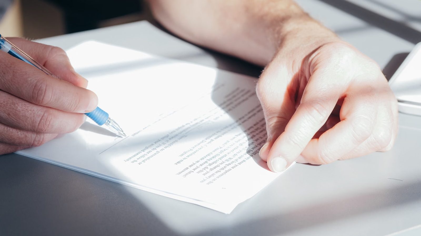 Hand signing a document with a pen
