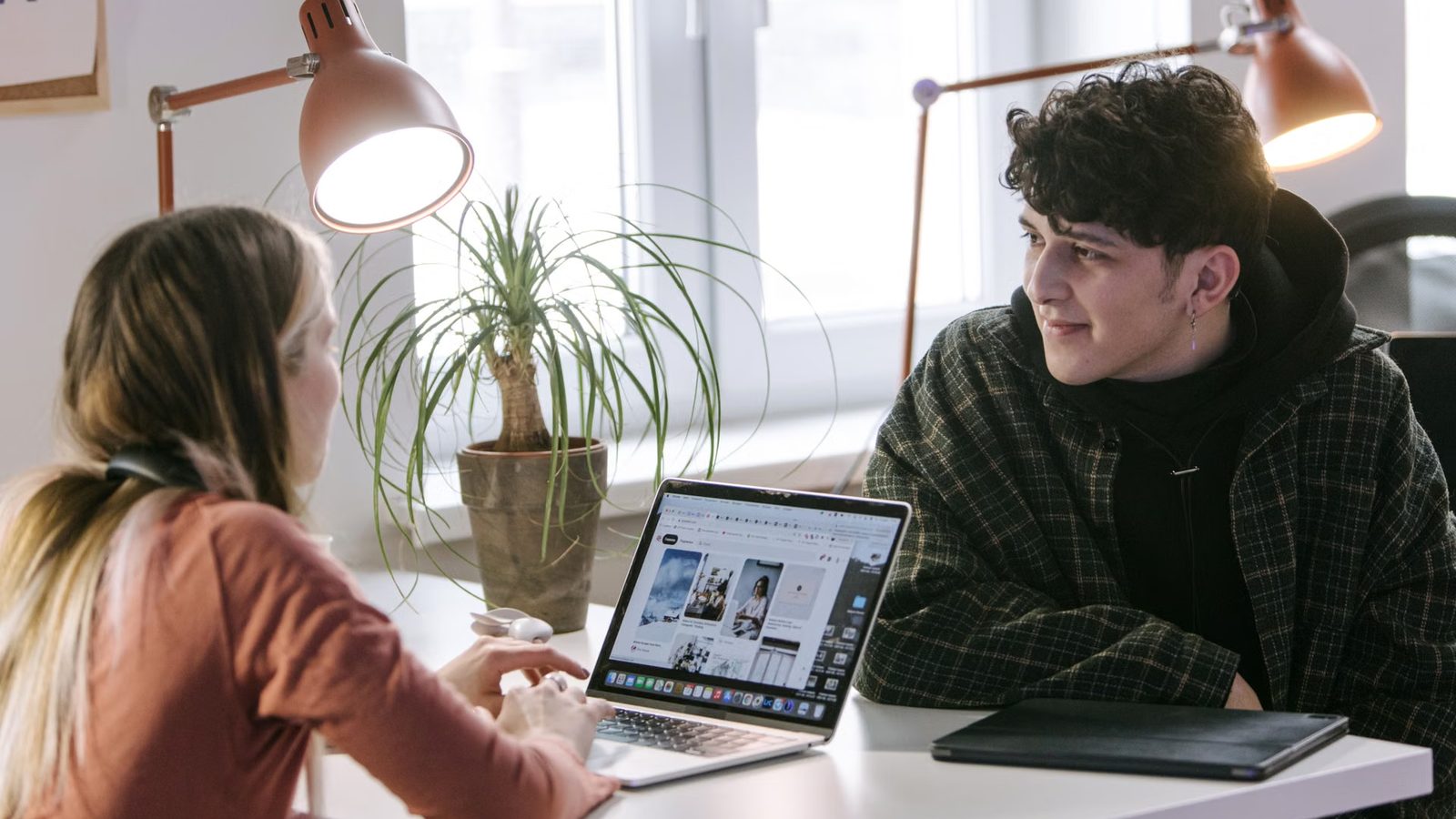 Two people talking at a laptop