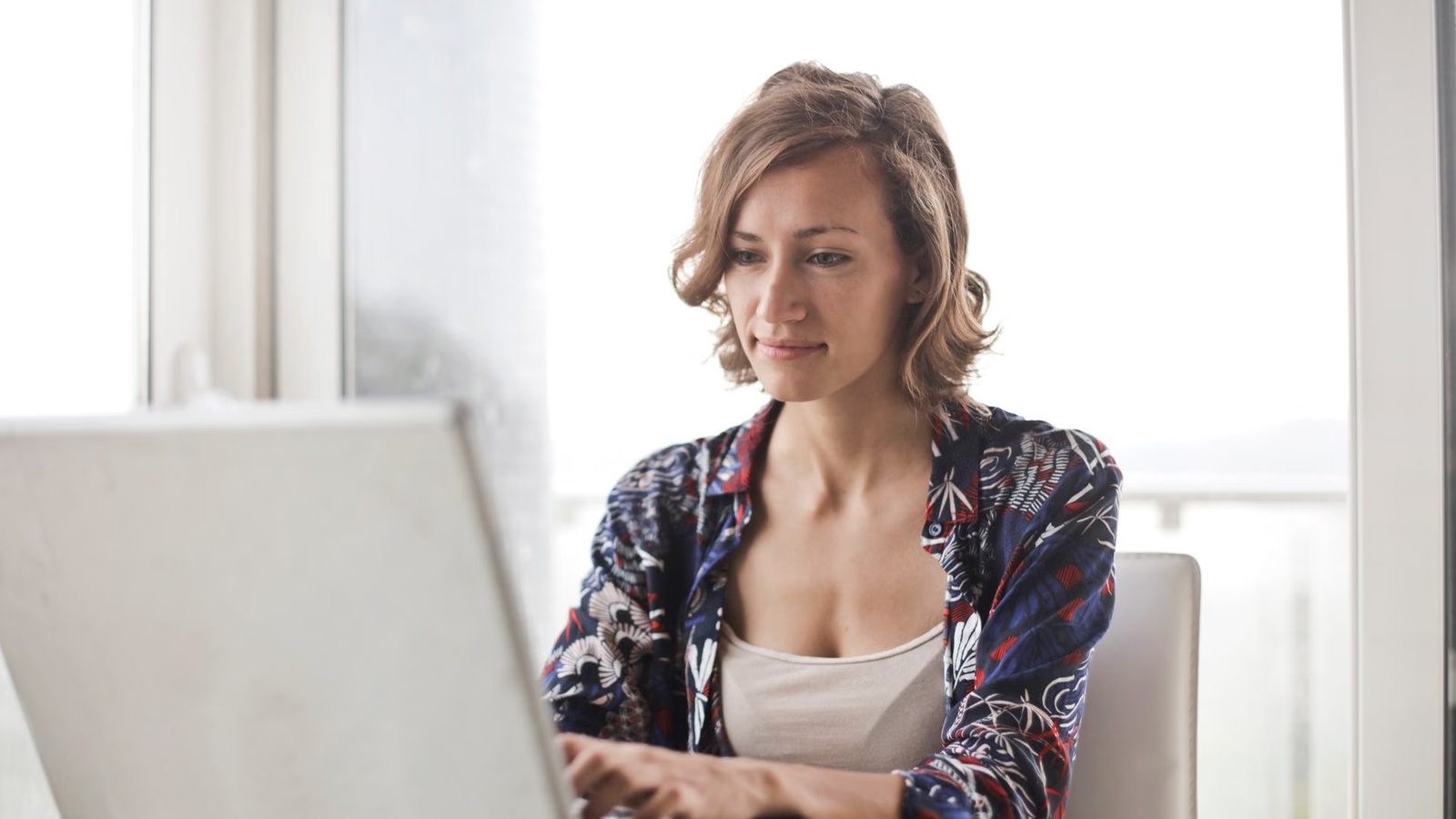 Writing text on a laptop next to a notebook