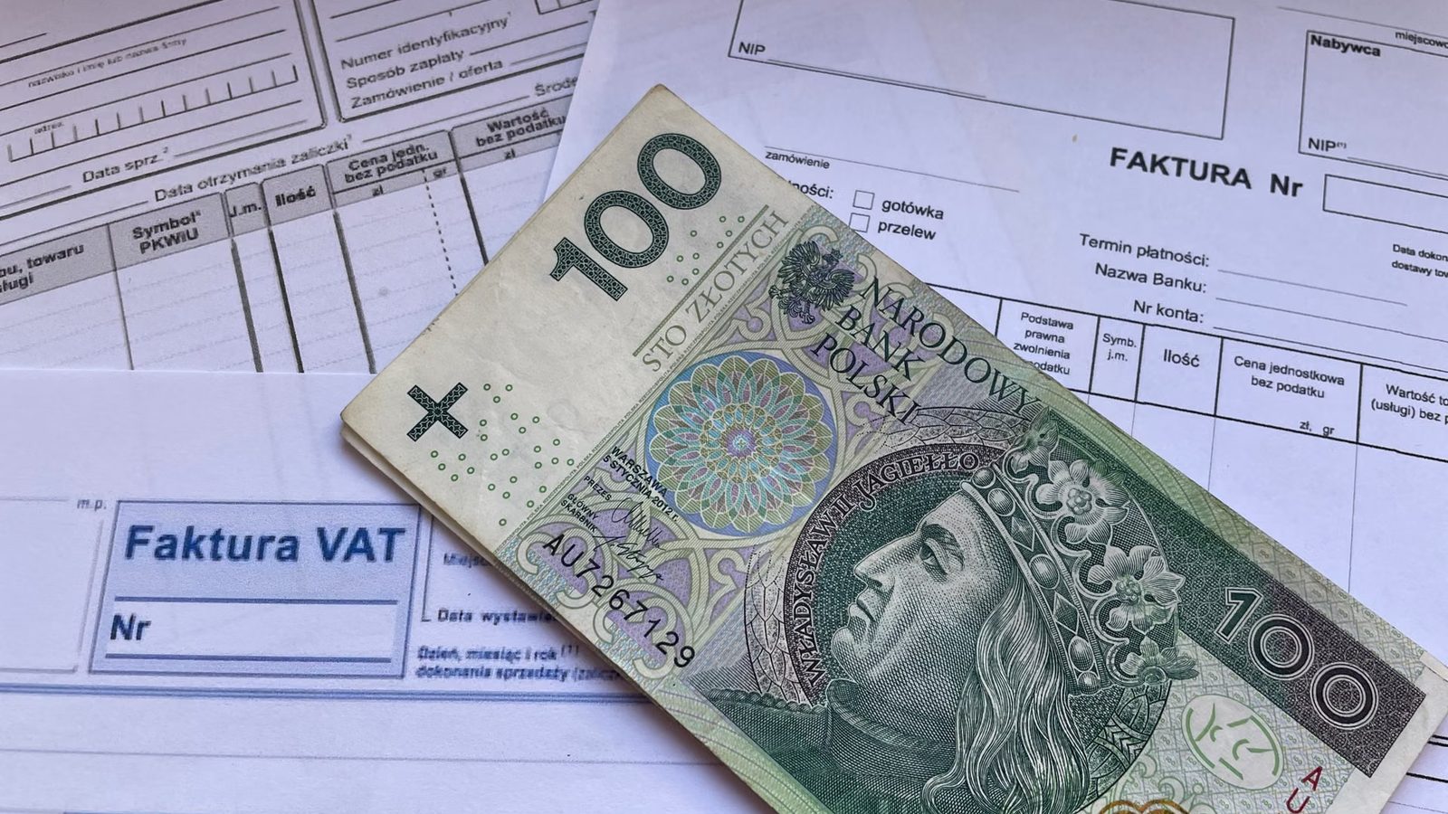 VAT invoice and a 100-złoty banknote on a desk